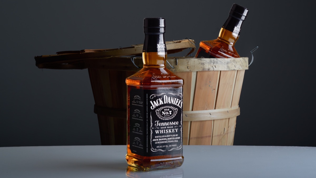 Bottles of Jack Daniel's on table and in a barrel