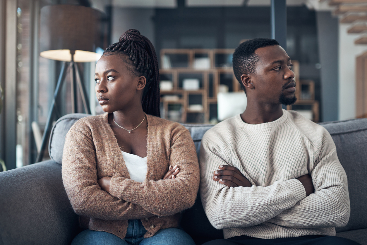 young couple sitting on the sofa and giving each other the silent treatment after an argument