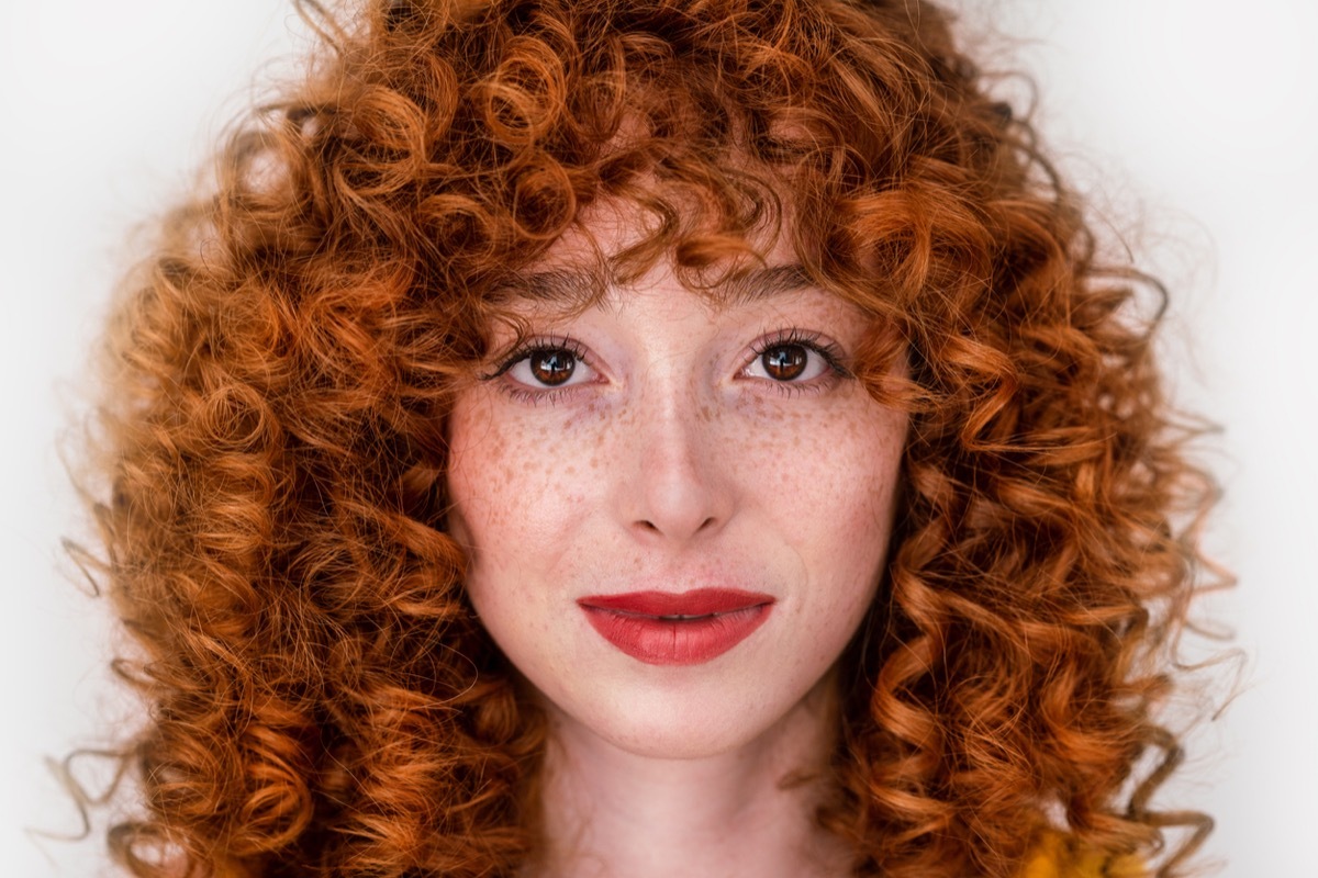 Face of a beautiful woman with red hair and lips isolated on green background. High quality photo