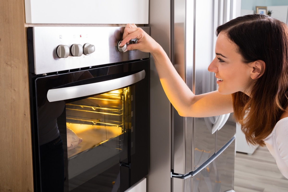 Woman turning dial on oven while cooking