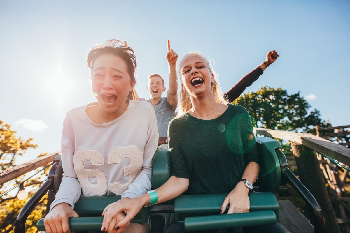 Friends on a rollercoaster one scared and screaming another excited laughing