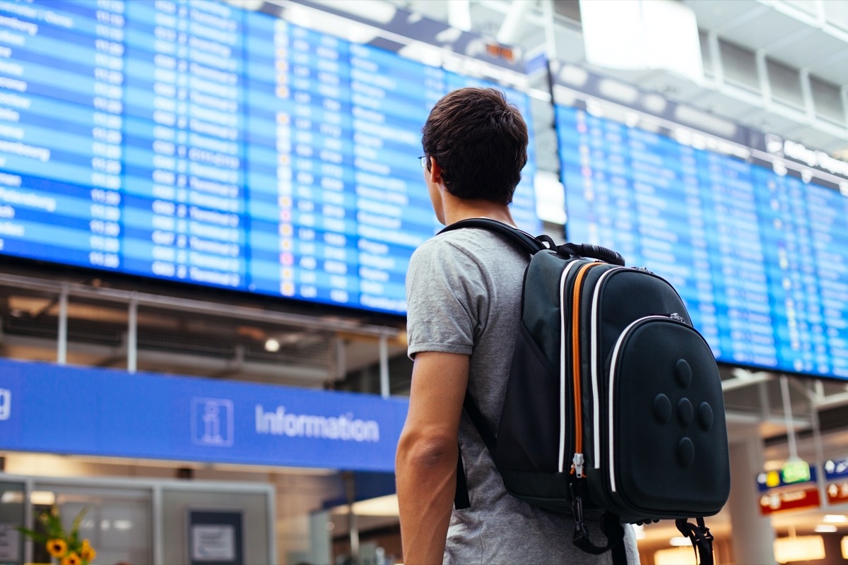 man in airport looking at his flight details