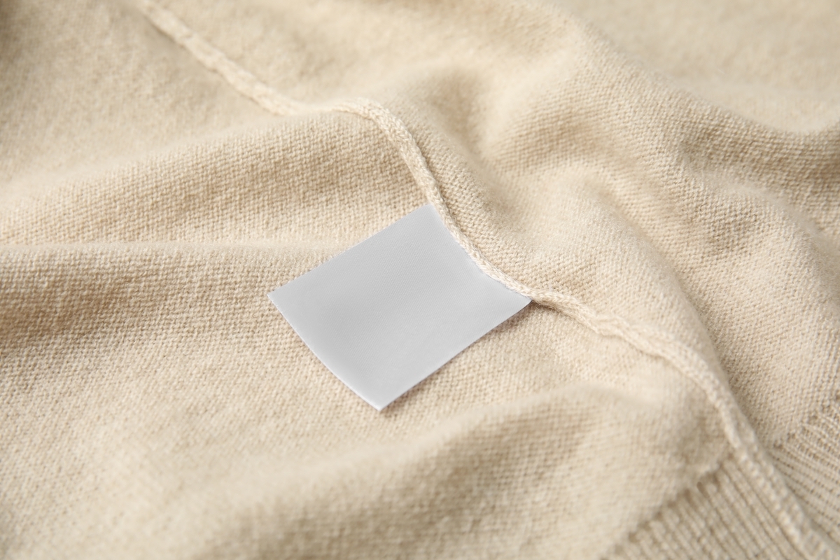 Closeup of the seam and tag on a beige sweater.