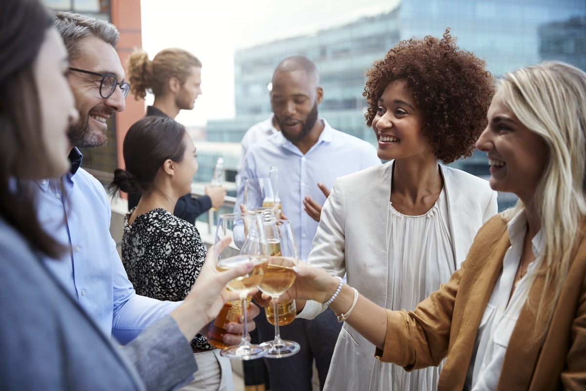 men and women who work together toasting beer and wine outside