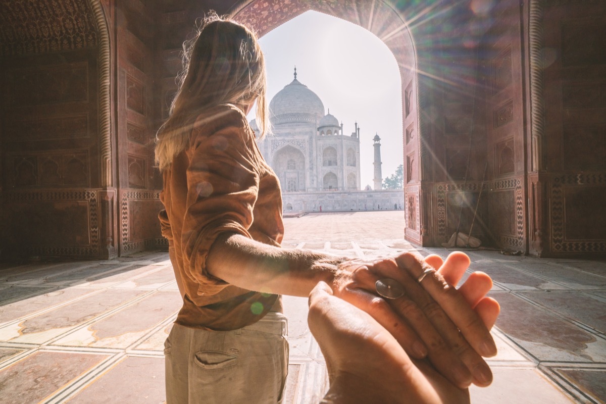 follow me to the Taj Mahal, India. Female tourist leading boyfriend to there magnificent famous Mausoleum in Agra. People travel concept