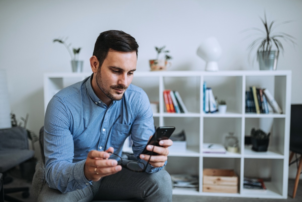 Man looking at his phone in a blue business shirt