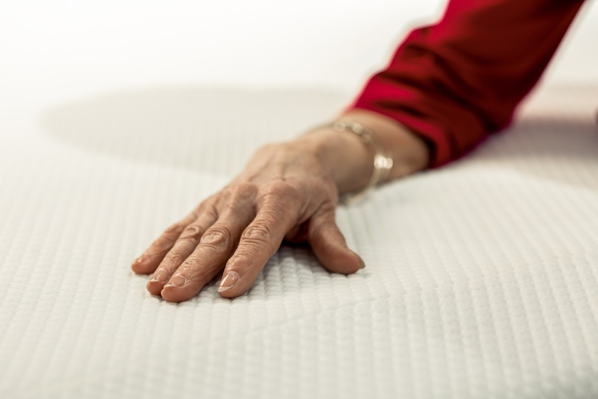 older woman placing her hand on memory foam mattress, NASA everyday items