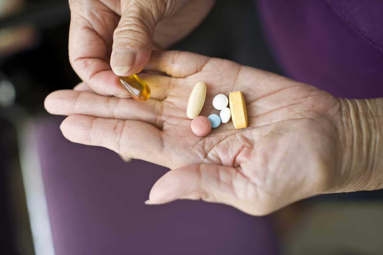 A senior person's hands holding supplement pills