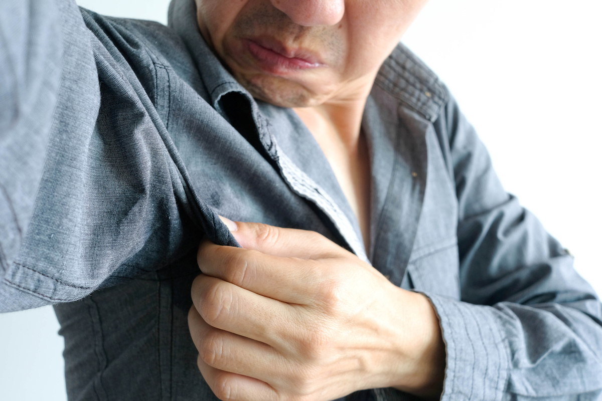 Men wears shirt and raises arms are covered with armpits to see if he smells