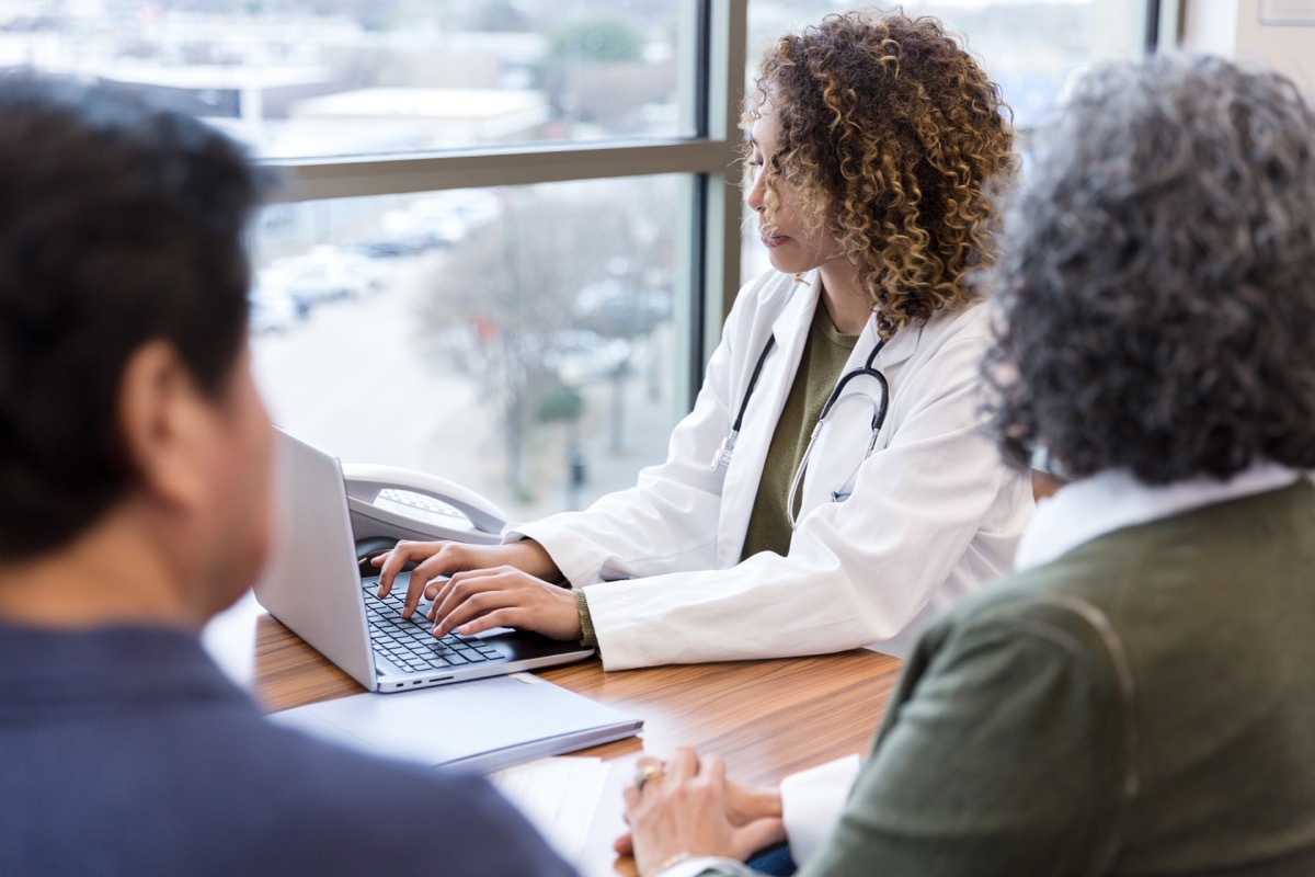 senior couple sitting across the table while doctor is typing