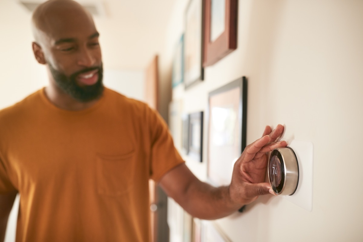 man turning down thermostat