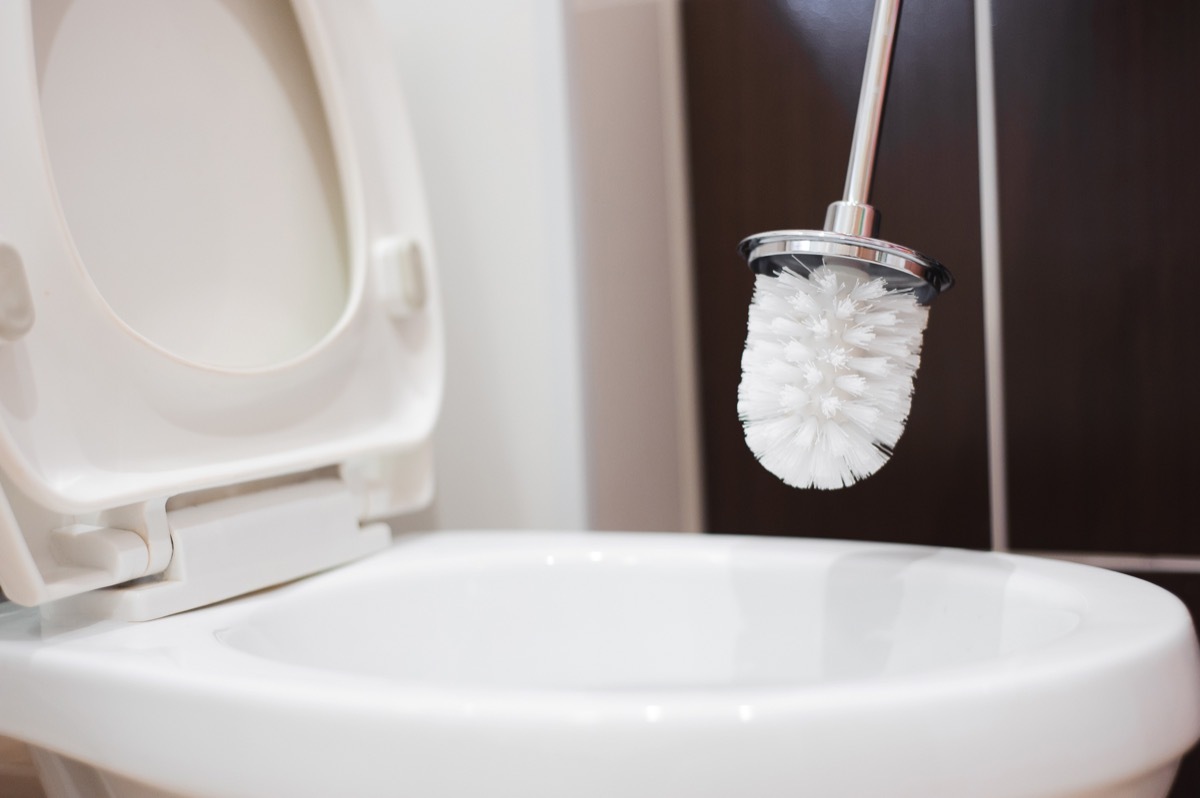 cleaning toilet with white toilet brush