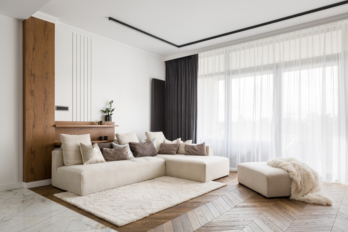 Elegant and comfortable designed living room with big corner sofa, wooden floor and big windows