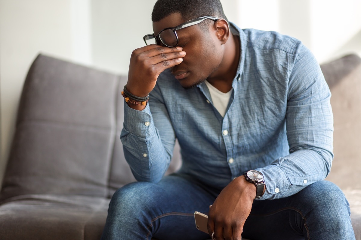 Tired man rubbing his eyes or head on the couch