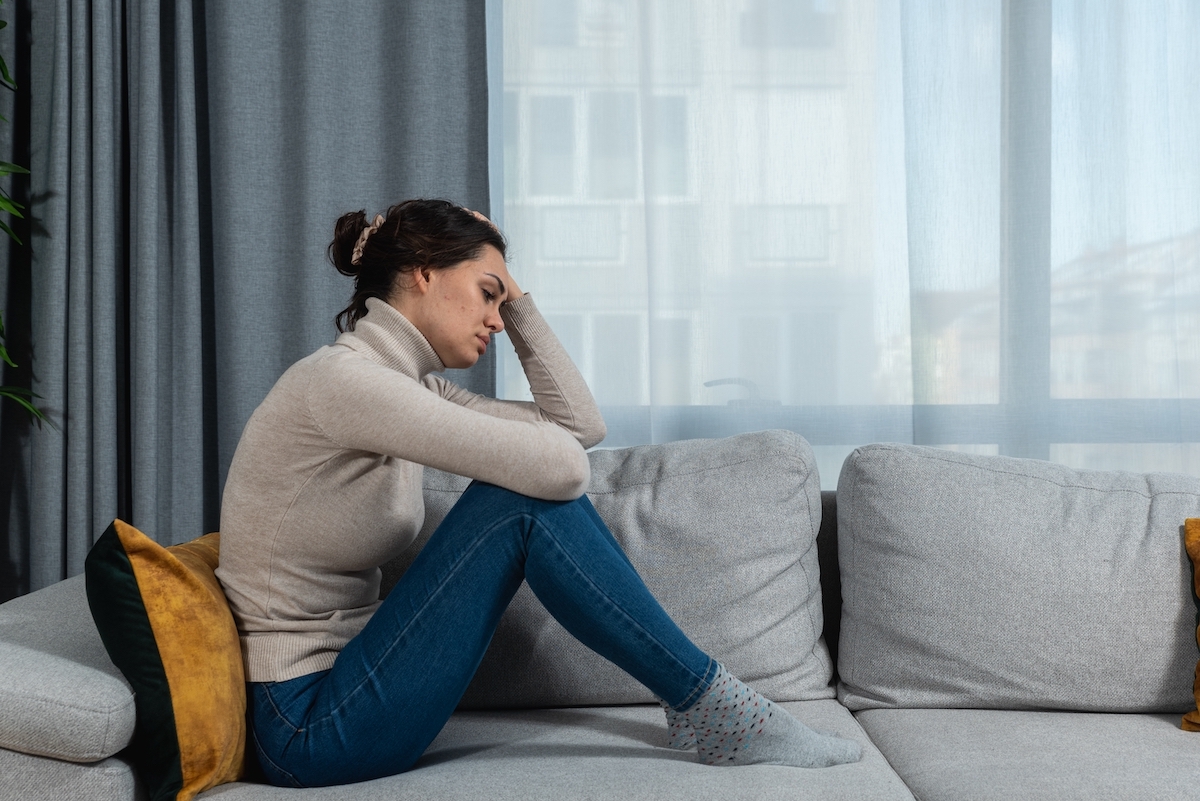 A sad-looking woman curled up on the couch