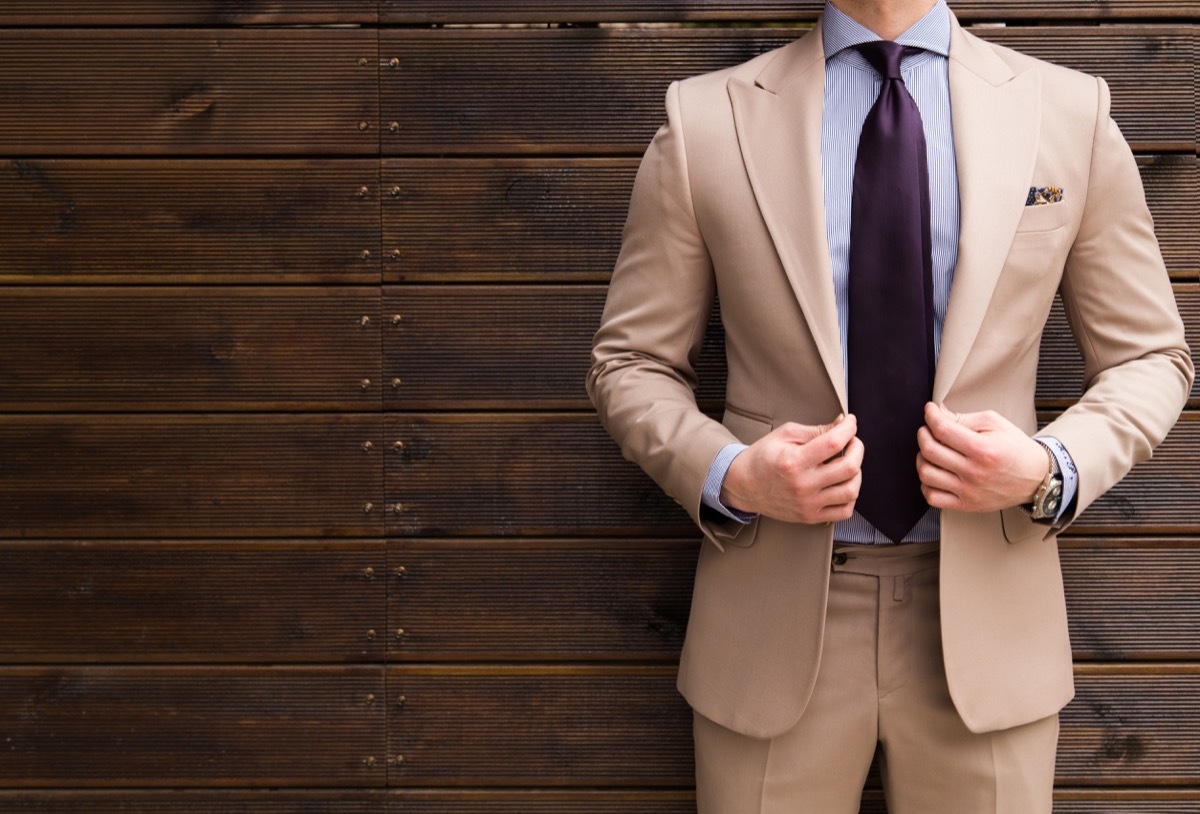 man wearing a tan suit and a purple tie