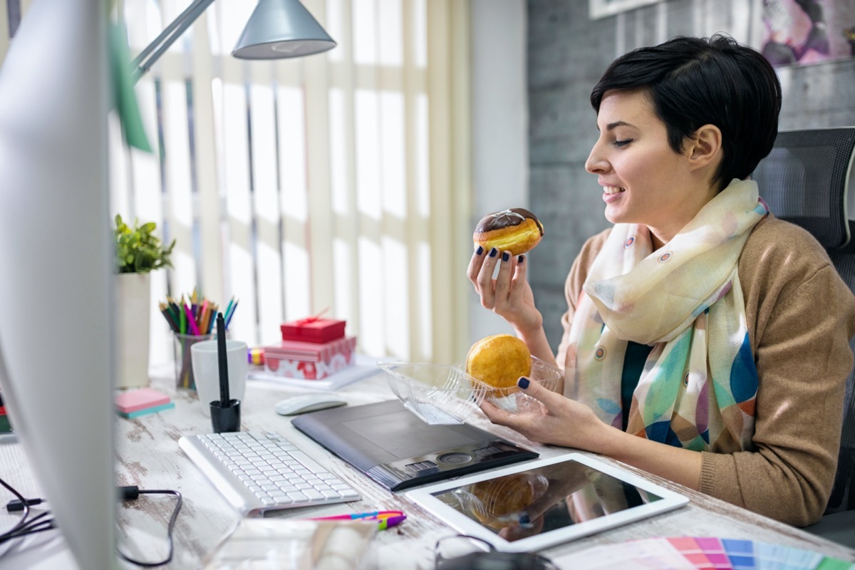 satisfied designer eating donuts in office