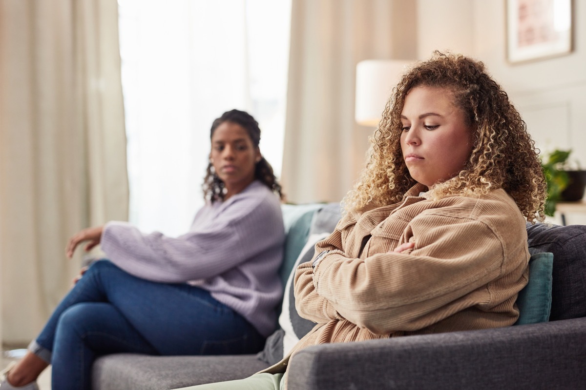 Shot of a young woman sitting on the sofa and ignoring her girlfriend after an argument