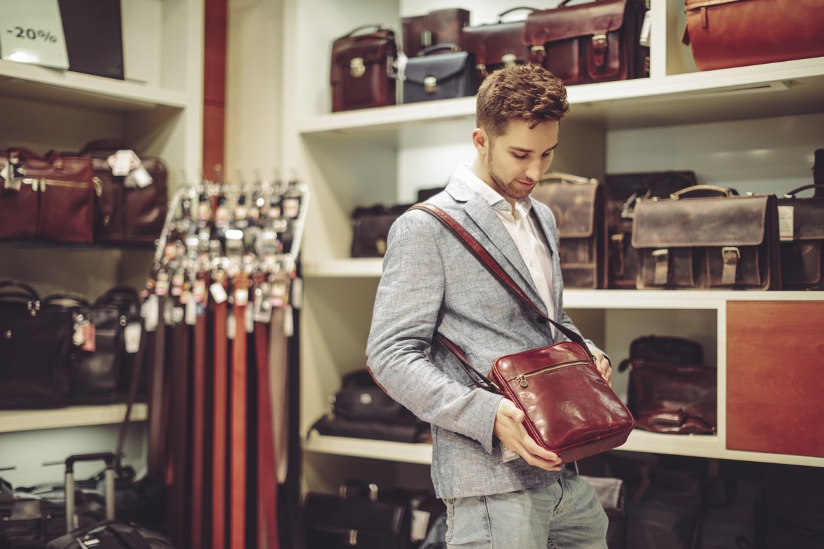 man standing with satchel he cannot afford in a store