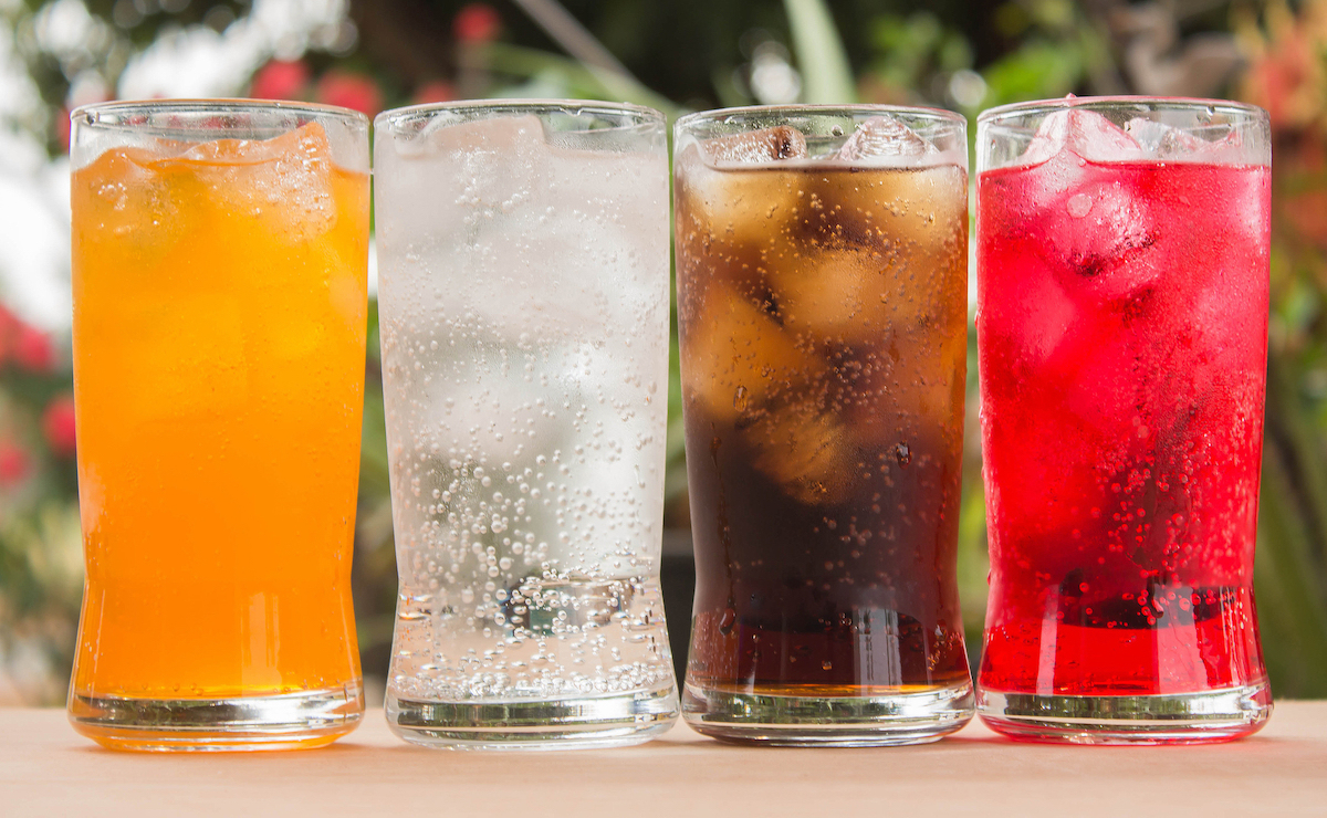 orange soda, seltzer, soda, red soda on wood table in glasses