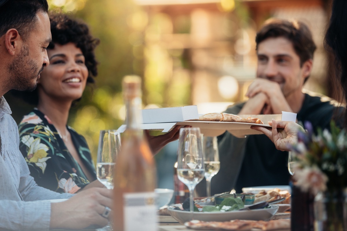 host passing a dish between friends at a dinner party