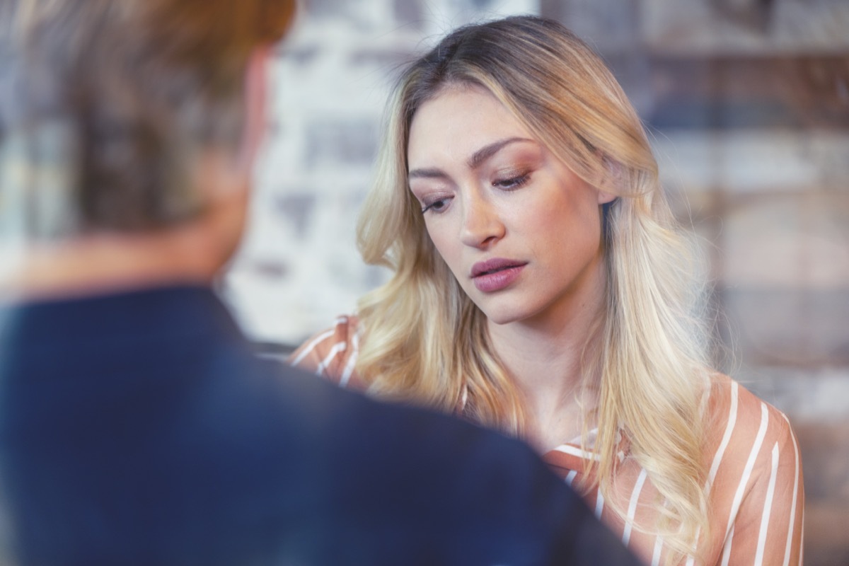 Woman in an interview. She is looking sad and upset. She could be talking to a mental health doctor, or in a job interview. She is looking down