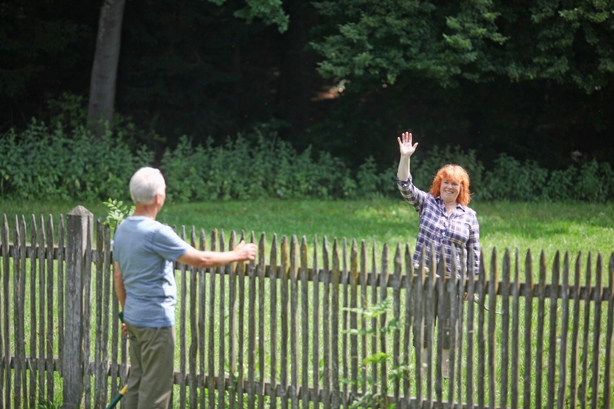 Neighbors greeting each other over fence