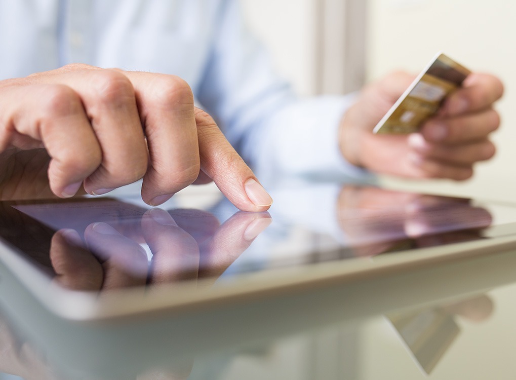 closeup of man's hand clicking on item on tablet while online shopping