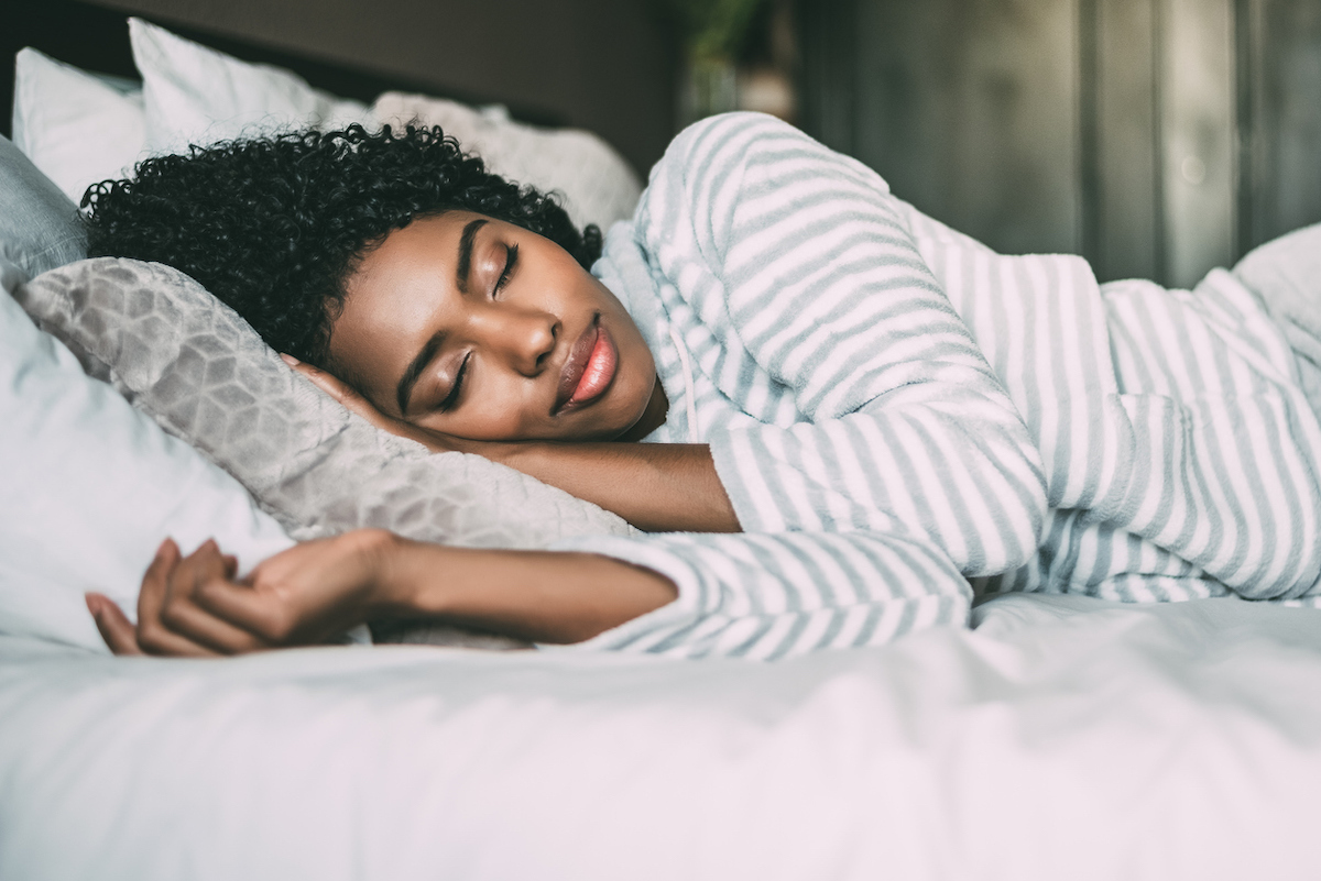 close up of a pretty woman with curly hair sleeping in bed closed eyes