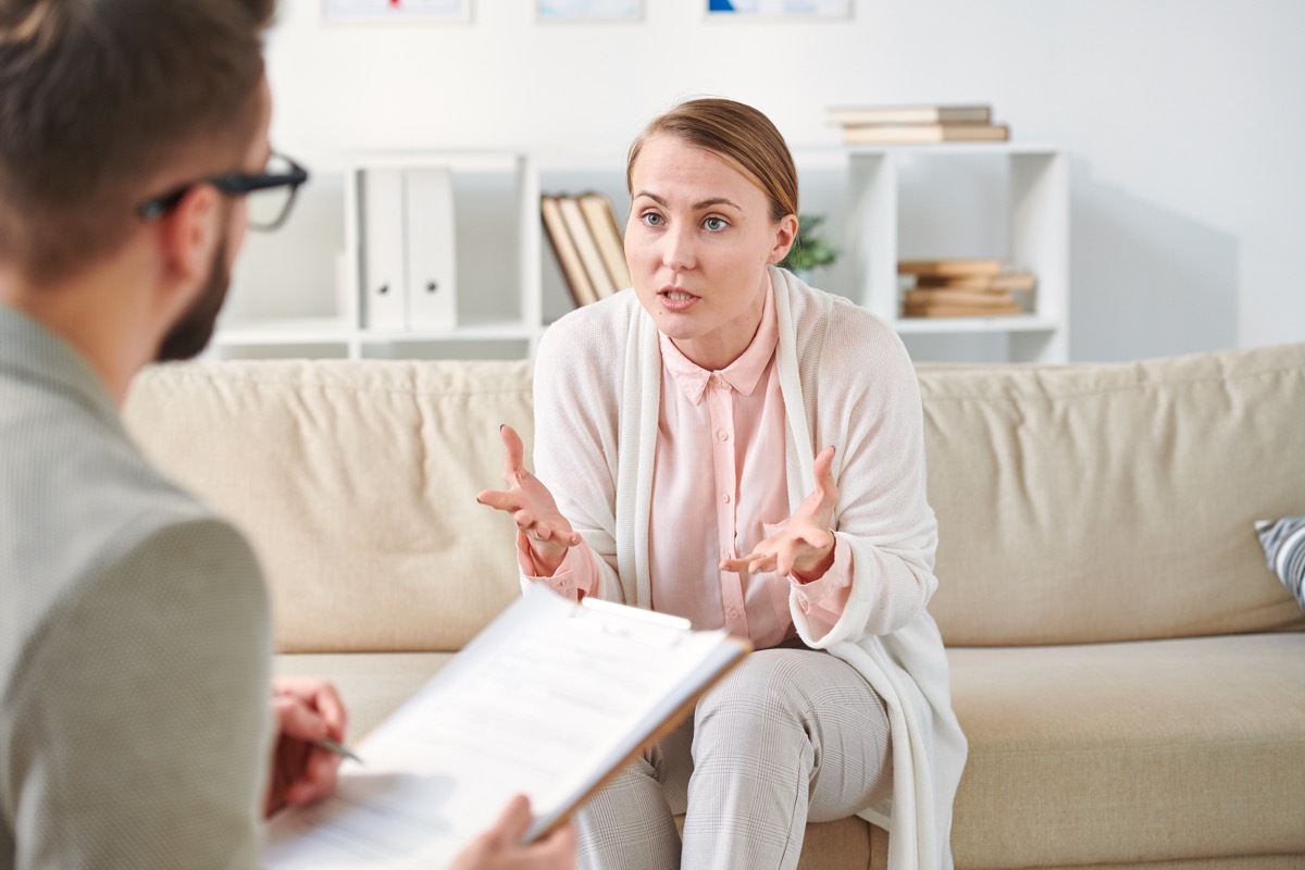 patient of counselor explaining her problem to doctor while sitting on couch in front of him