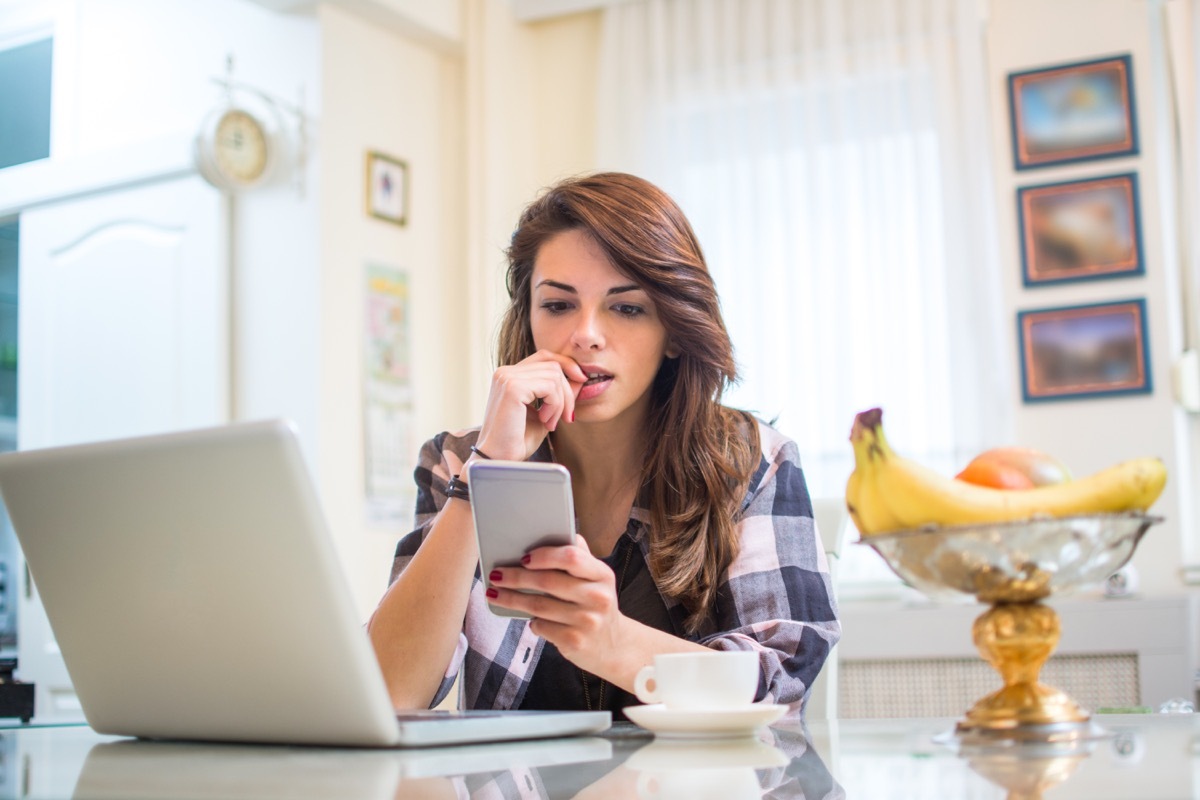 young white woman biting nails in kitchen