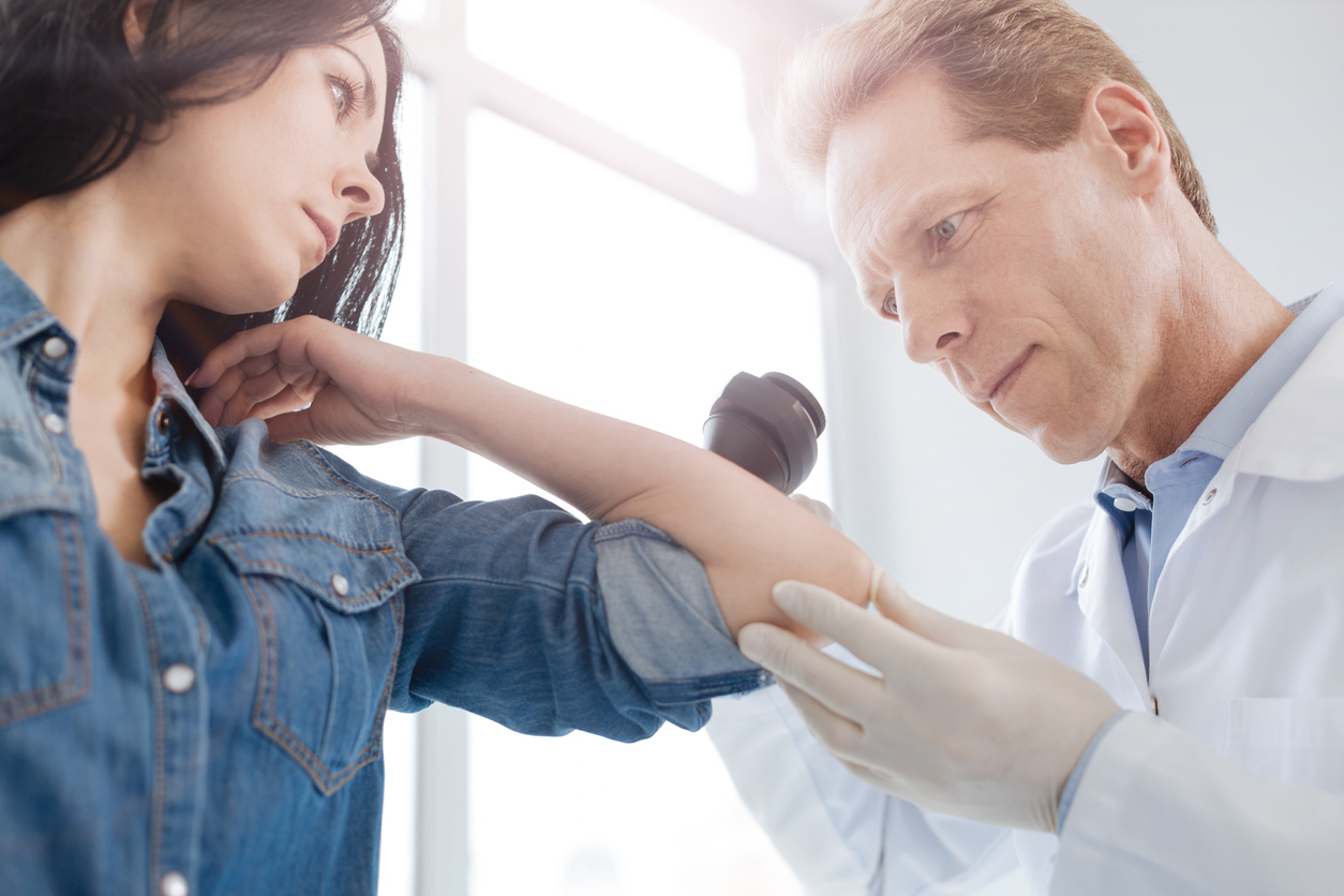 Doctor examining woman's skin.