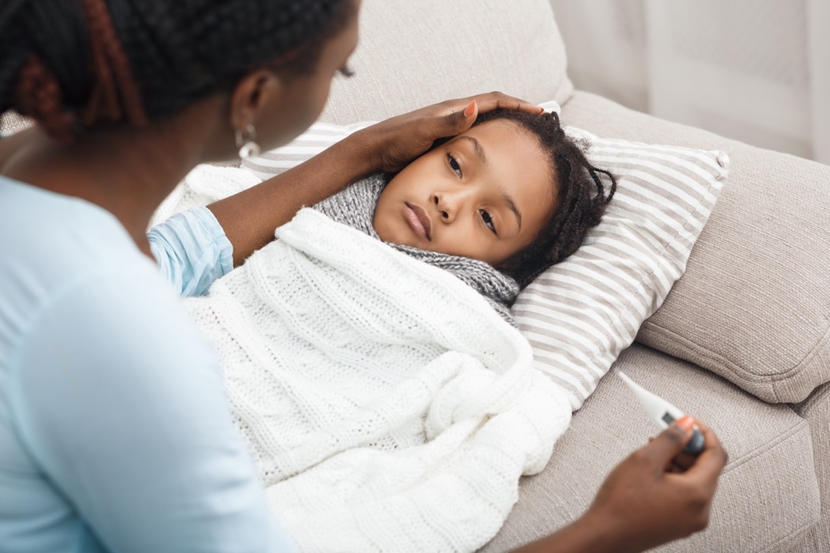 Sick child in bed, mother holding thermometer, comforting poor girl