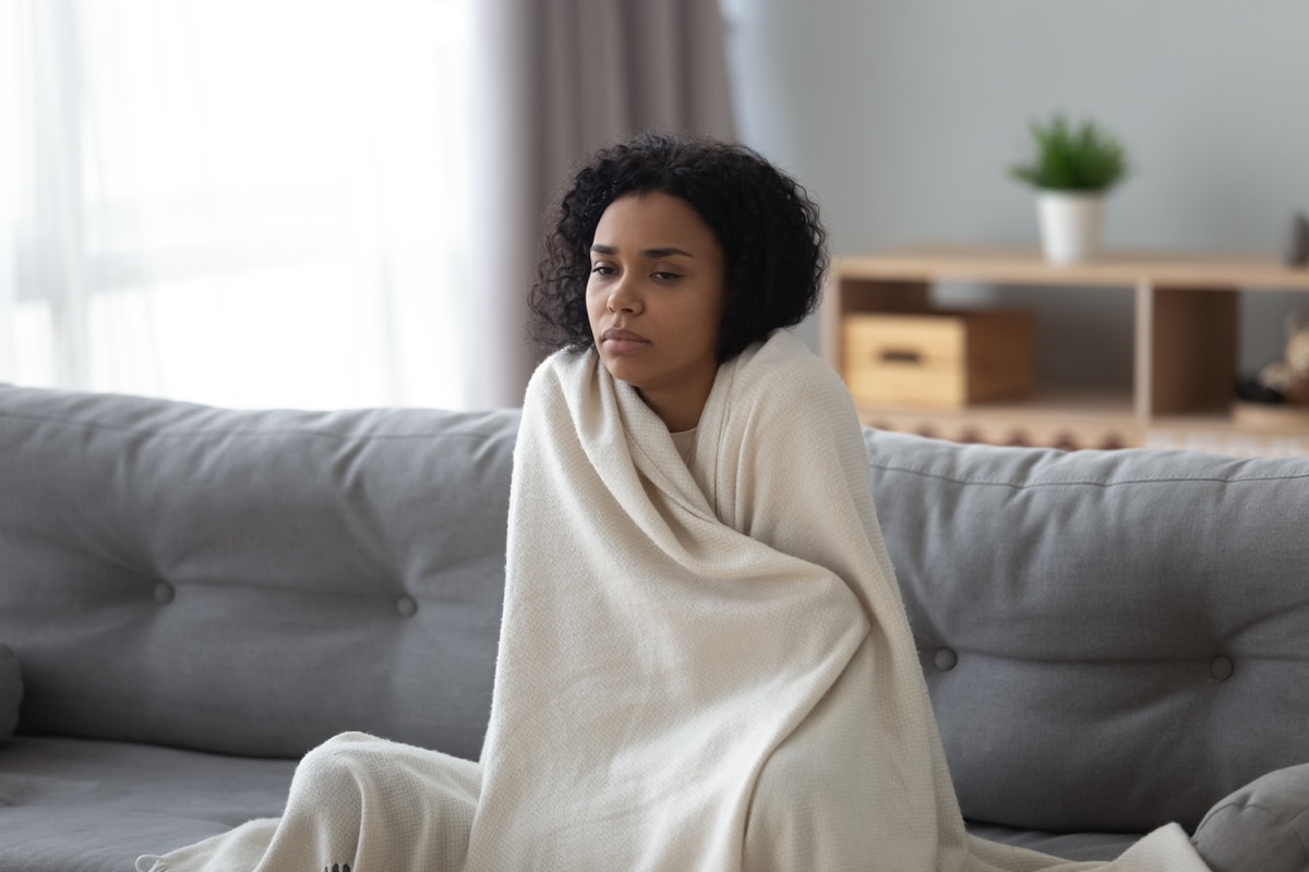 Woman shivering under a blanket because she is so cold