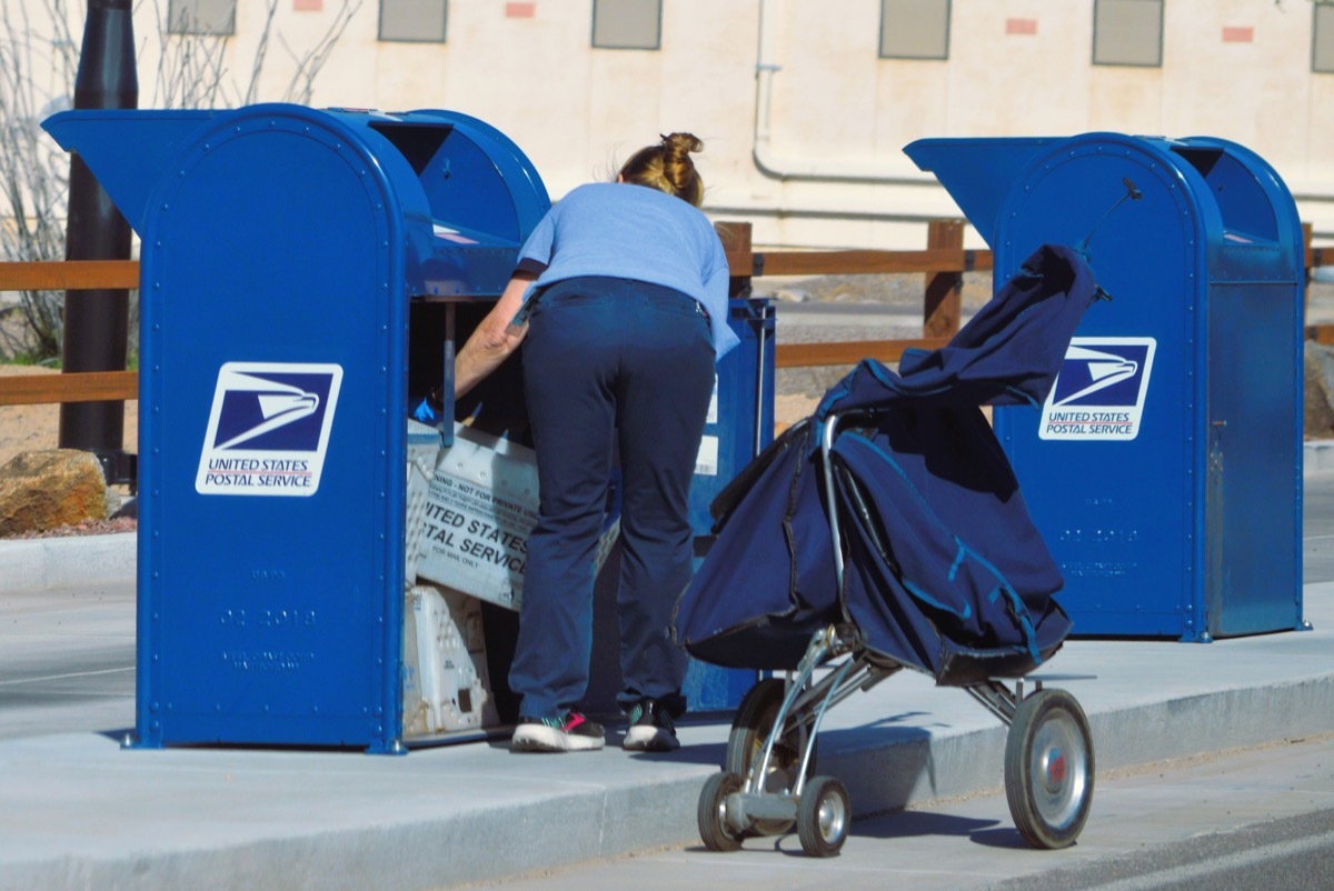 April 04 2023: A USPS postal worker collects the outgoing mail at a drive thru drop off box.