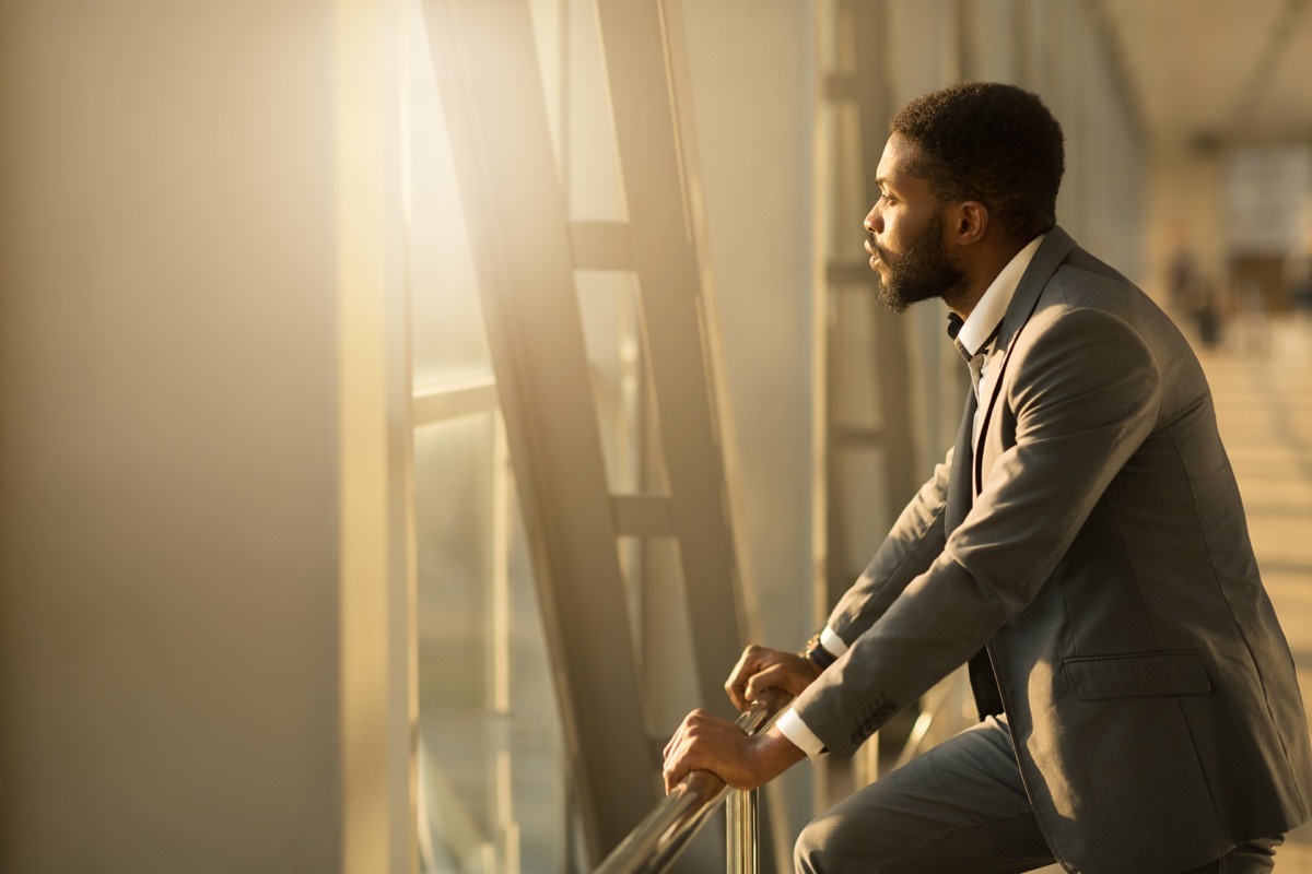 man gazing wistfully out an airport terminal window