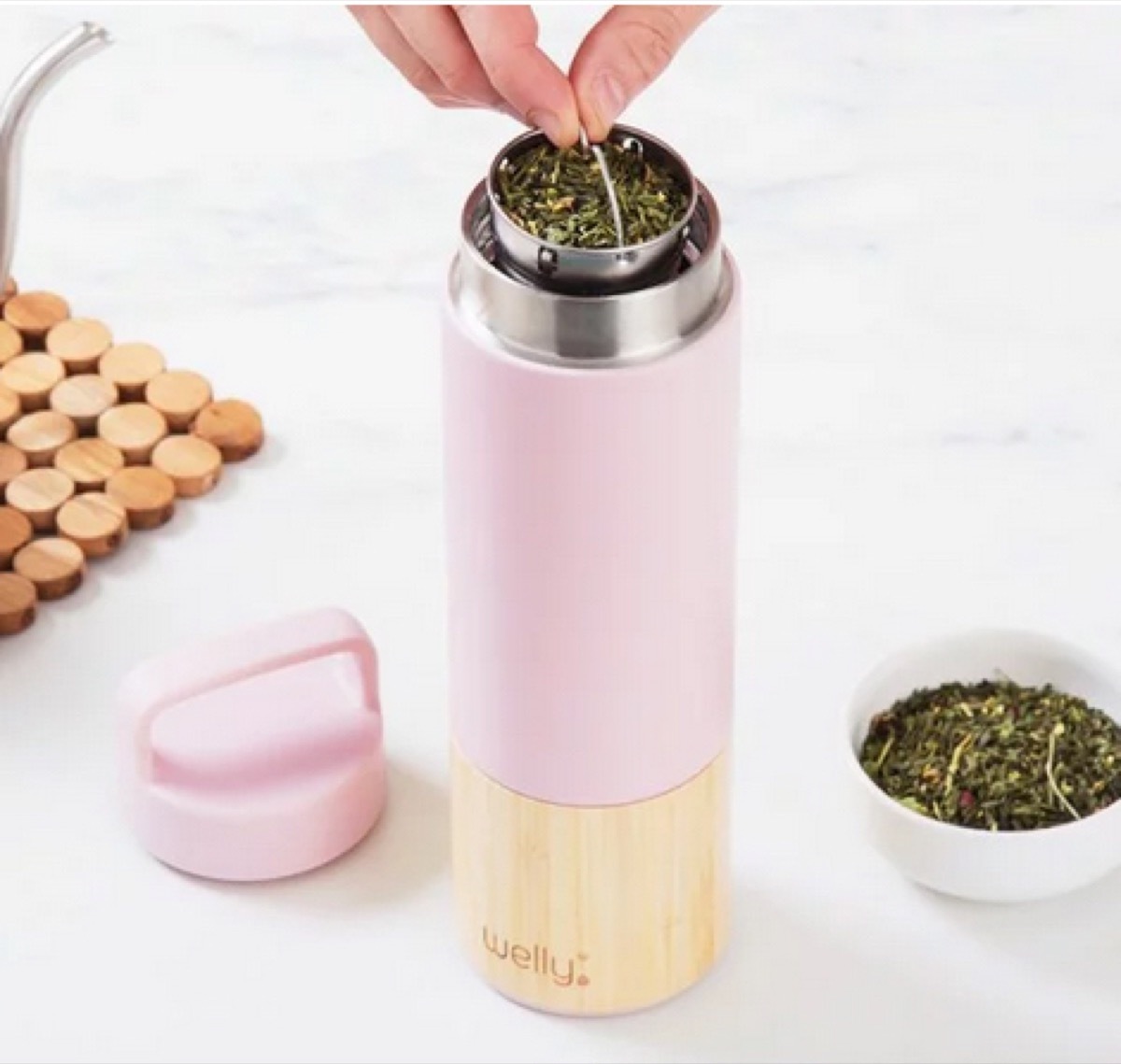 white hand holding metal basket of pink infuser bottle