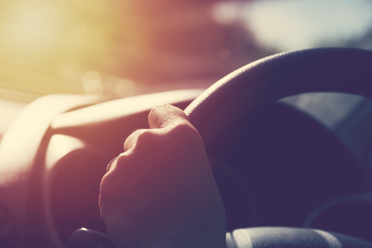 Female hand on steering wheel.