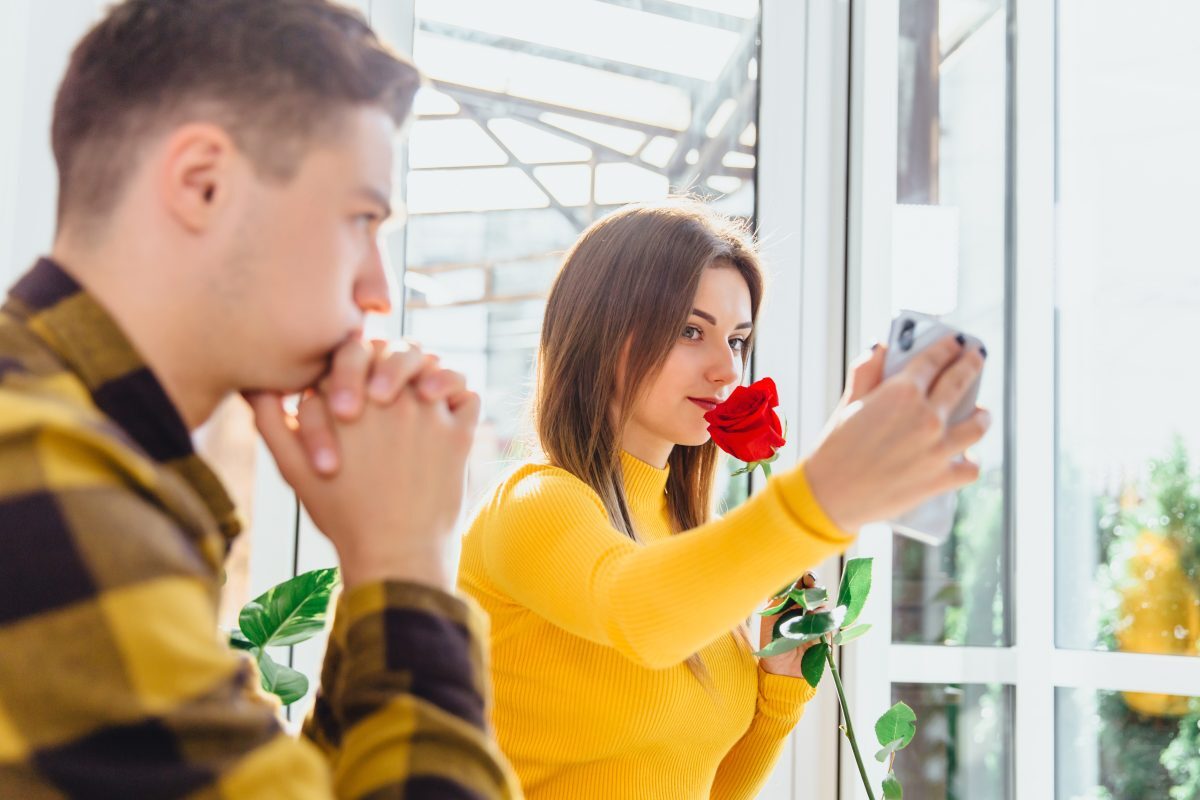 young woman taking selfie while partner watches