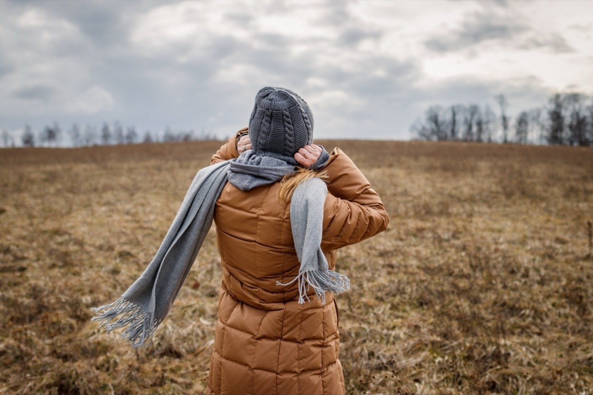 Woman wearing coat, scarf and knit hat outdoors in nature