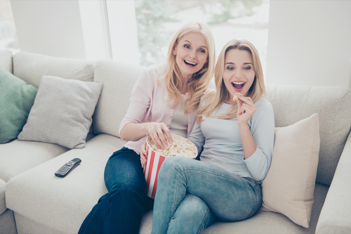 two women watching tv on couch