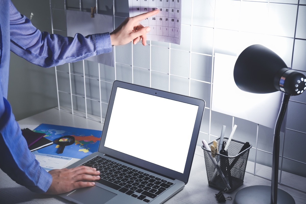 Man with laptop looking at calendar to schedule