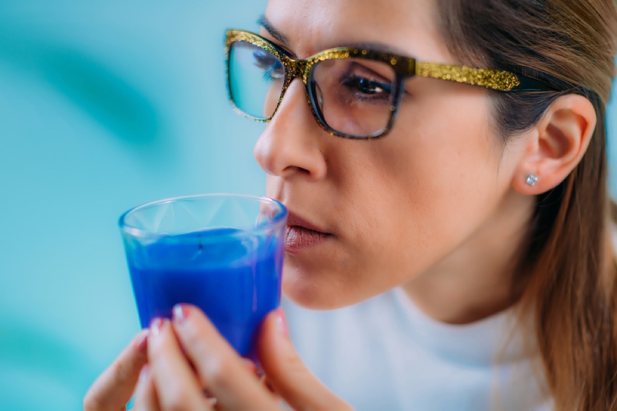 close up of woman smelling a candle and looking confused