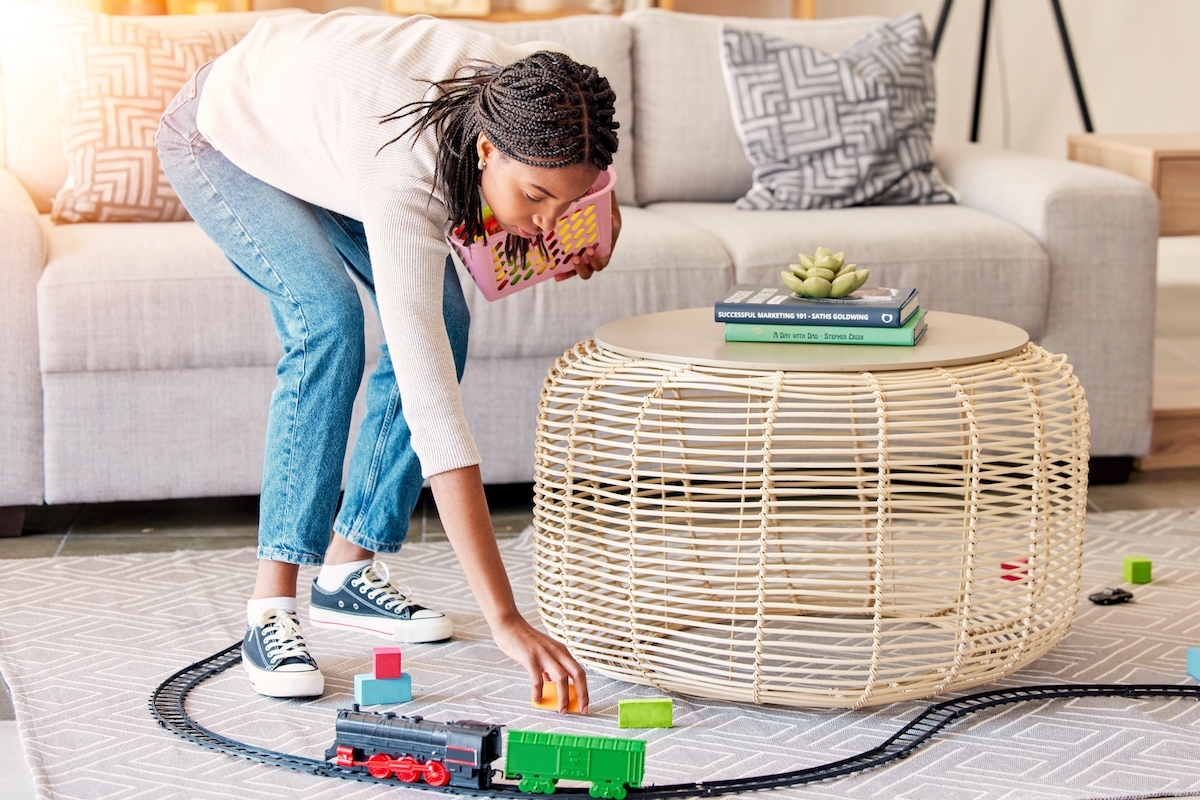 A woman cleaning up toys from the living room floor