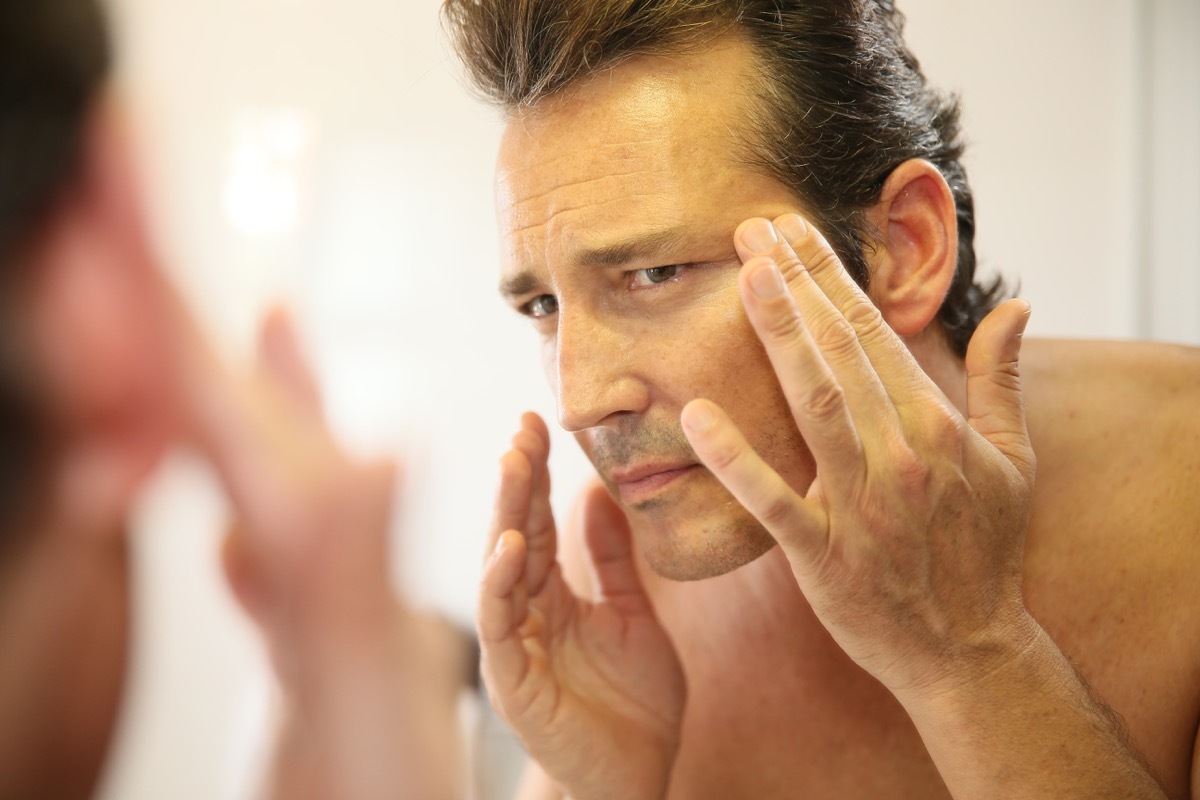 Man looking at his wrinkles in the mirror