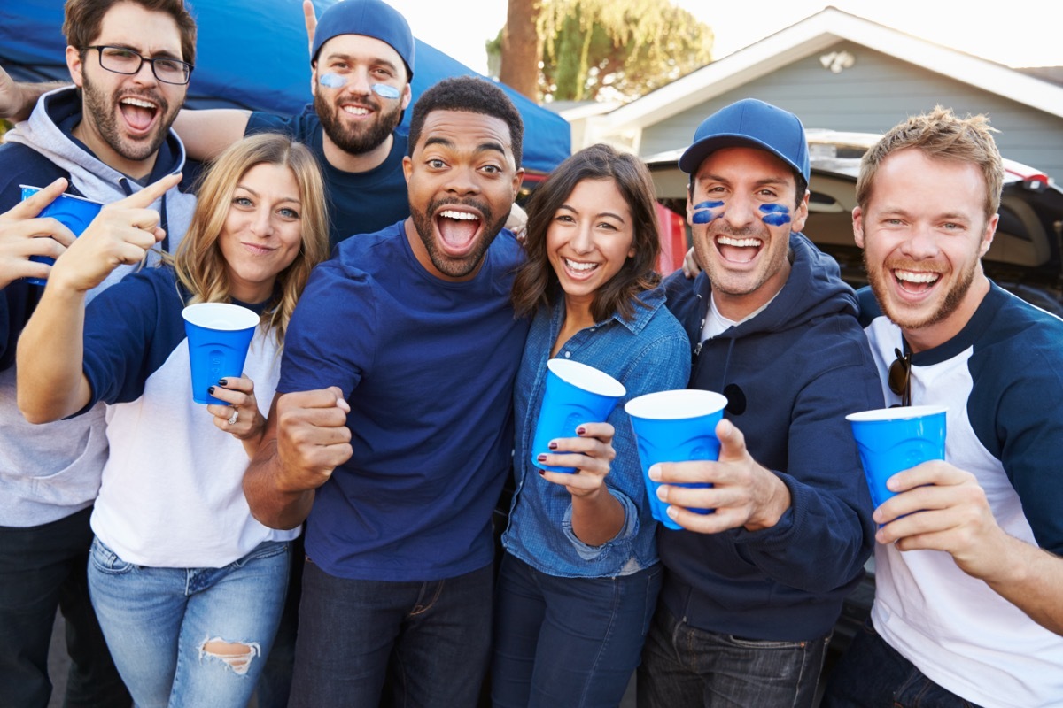 Group Of Sports Fans Tailgating In Stadium Car Park