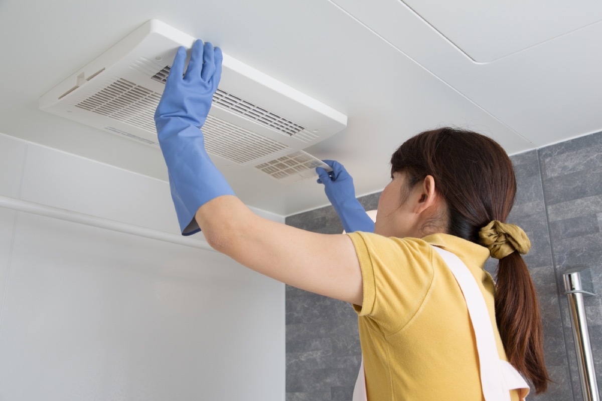 woman cleaning bathroom fan, signs your home is falling apart